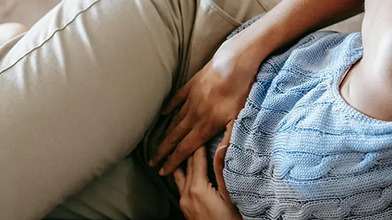 Woman holding a heat pad to ease period pain
